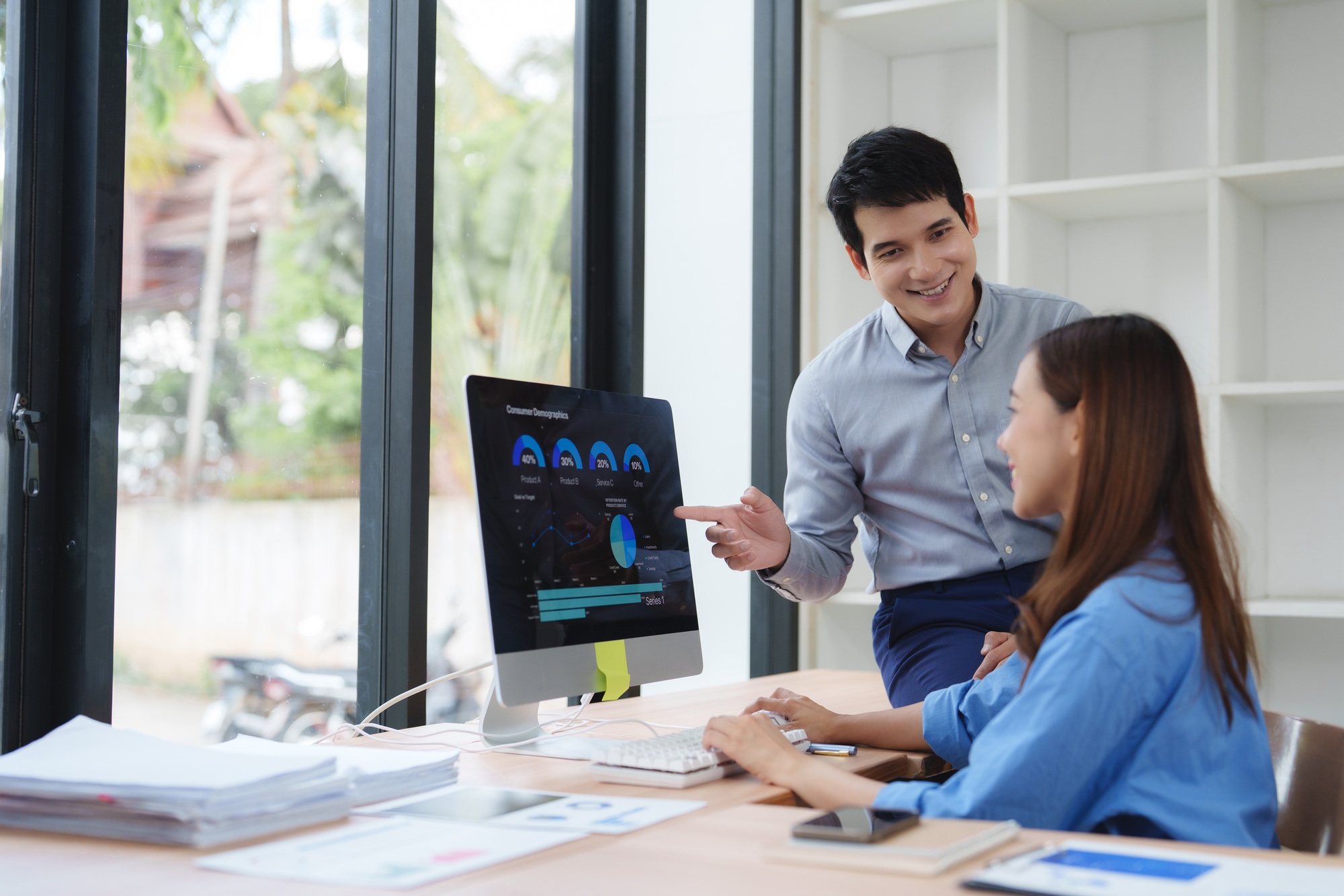 Two professionals discussing analytics on a desktop monitor