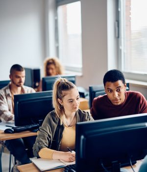 Young students cooperating while e-learning during computer class at the university.